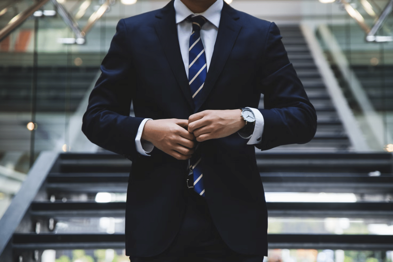 Person in suit adjusting tie on stairs.